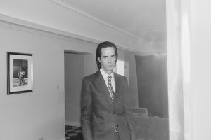 Nick Cave "smiles" with the 'Frogs' orchestra